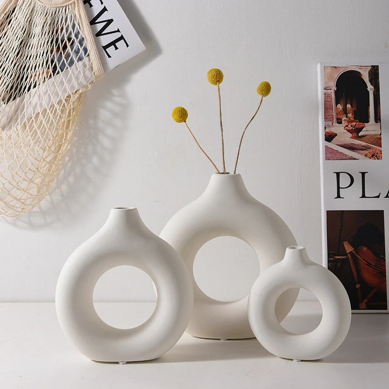 Set of three white ceramic vases with circular designs on a light background