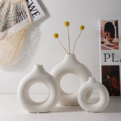 Set of three white ceramic vases with circular designs on a light background