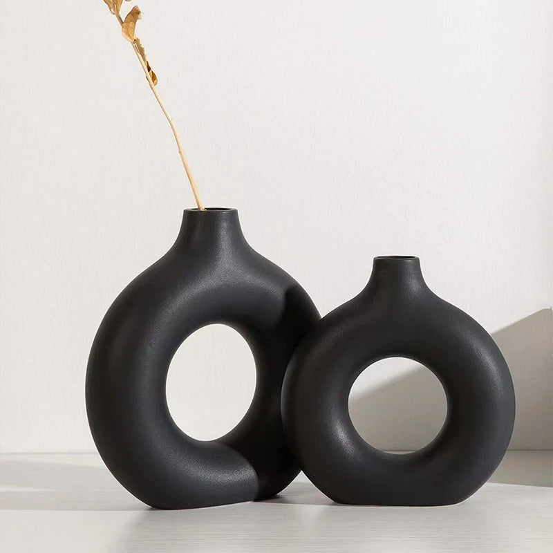 Two black ceramic vases with circular designs on a white background