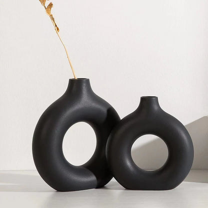Two black ceramic vases with circular designs on a white background